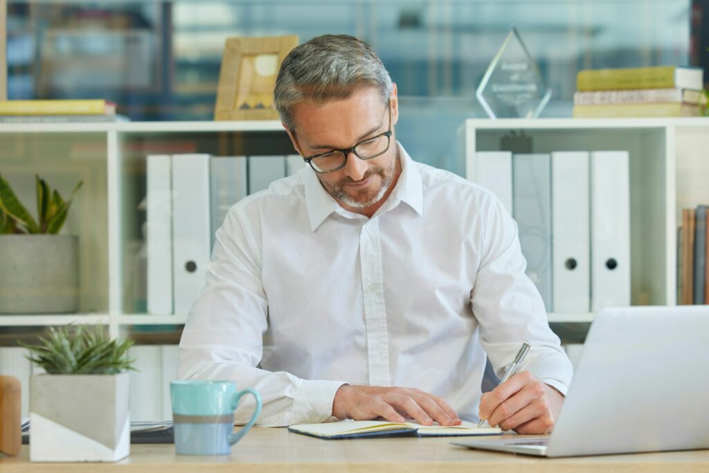 Businessman, writing in notebook and working in accounting firm for business tax, compliance and fi